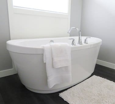 A white bath tub in a bathroom with a window