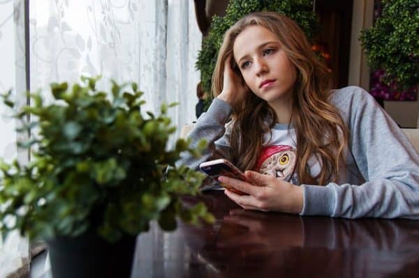 A young woman sitting at a table with a cell phone