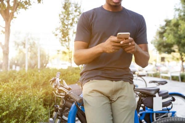 A man standing next to his bicycle and using his cell phone