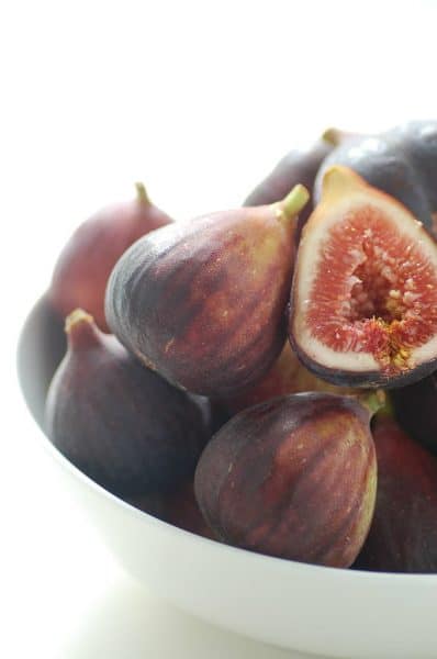 A bowl of figs on a white surface