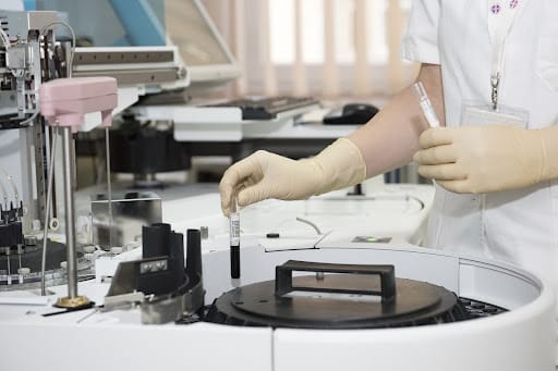 A person in a lab coat is working on a machine